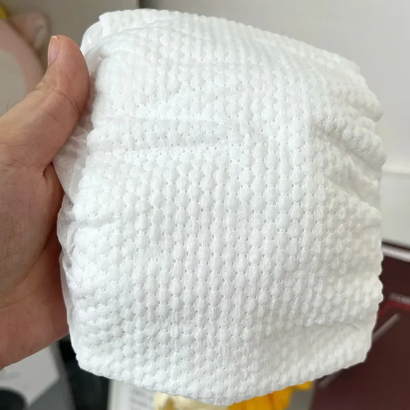 Hand holding topsheet emboss sample — diamond pattern