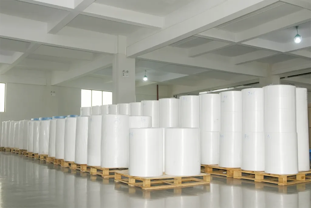 Large warehouse storing rolls of raw fabric material on wooden pallets, ready for quality inspection and production