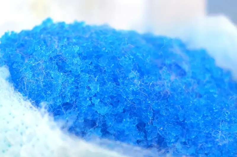 Close-up of blue super absorbent polymer (SAP) granules and fiber structure.
