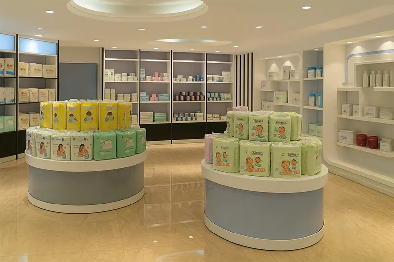 Showroom displaying stacks of baby diaper packages in yellow and green on round stands, with shelves of premium hygiene products in the background