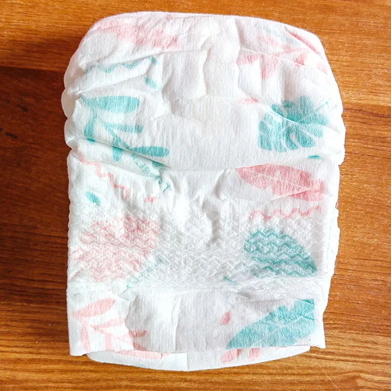 Flat-lay of a baby diaper on a wooden table—free trial pack included.