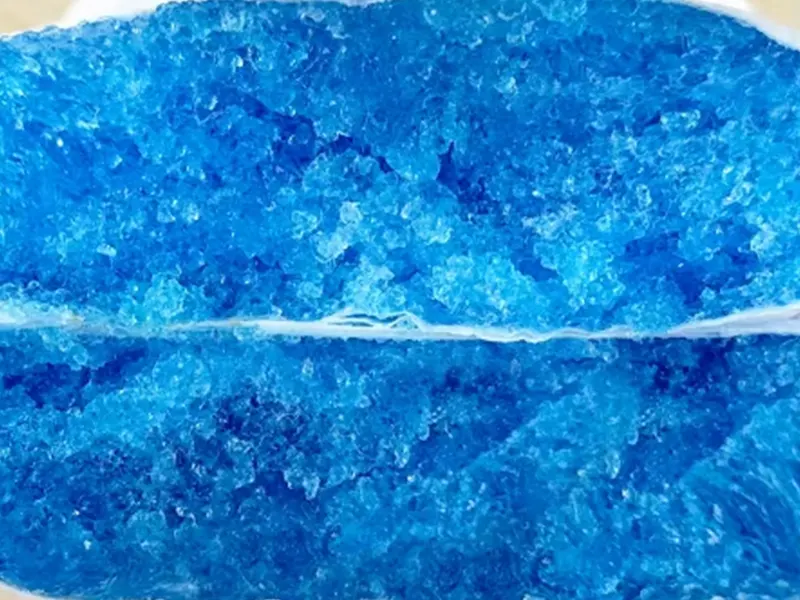 Close-up of blue super-absorbent gel core after liquid absorption inside a diaper.