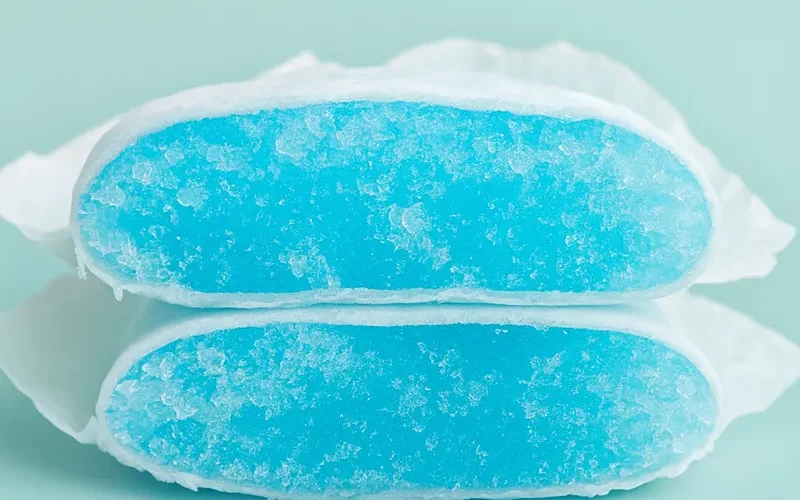 Close-up of diaper core cut open, showing blue superabsorbent polymer (first-use SAP)